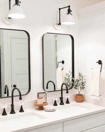 White bathroom cabinets with black mirrors and light fixtures.