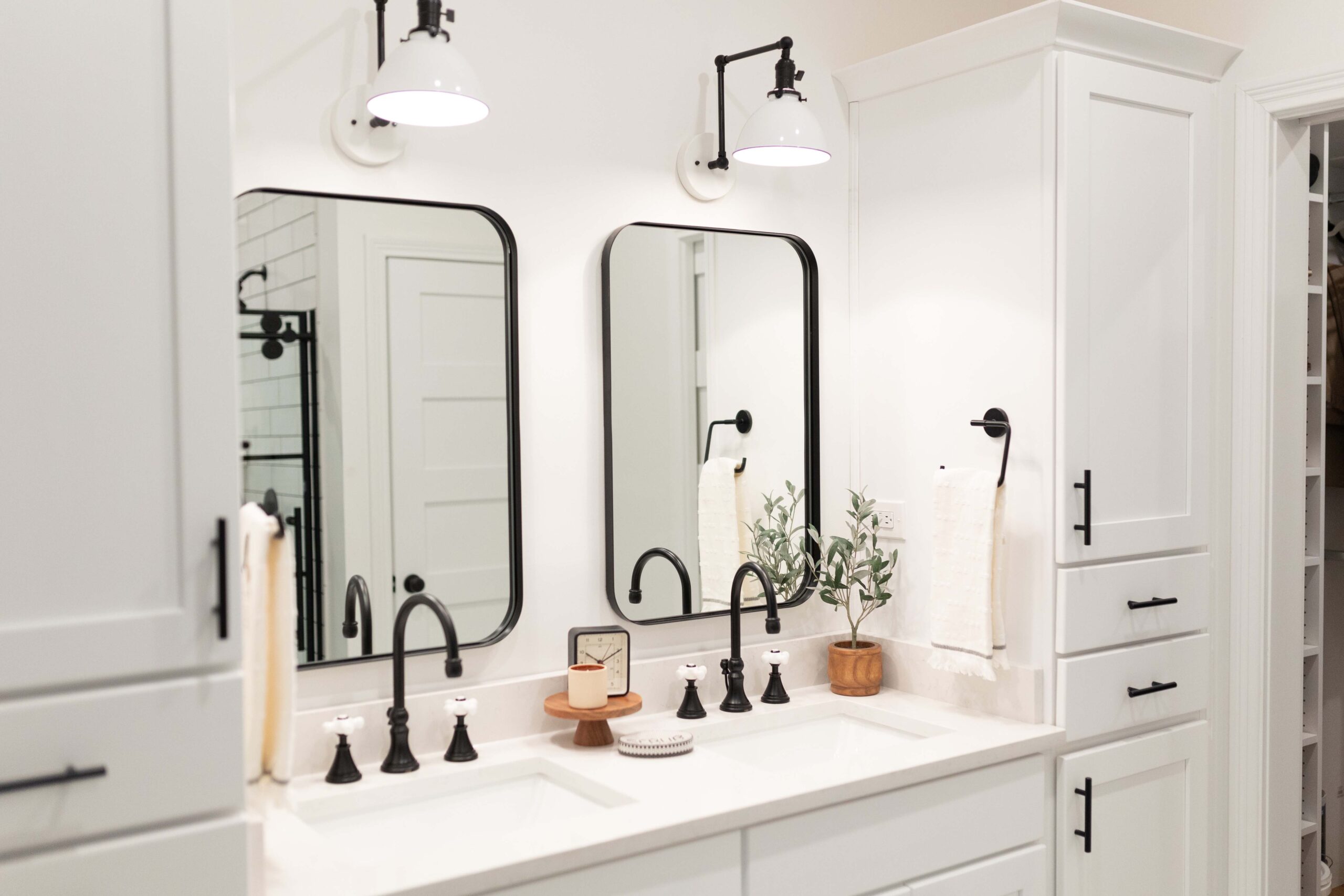 White bathroom cabinets with black mirrors and light fixtures.